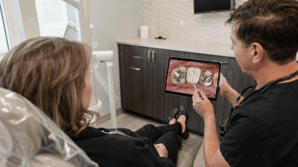 Dentist reviewing older fillings and crowns with a patient during a personalized dental restoration evaluation.
